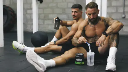 Dos atletas mezclan proteínas y aminoácidos en un mezclador después de entrenar