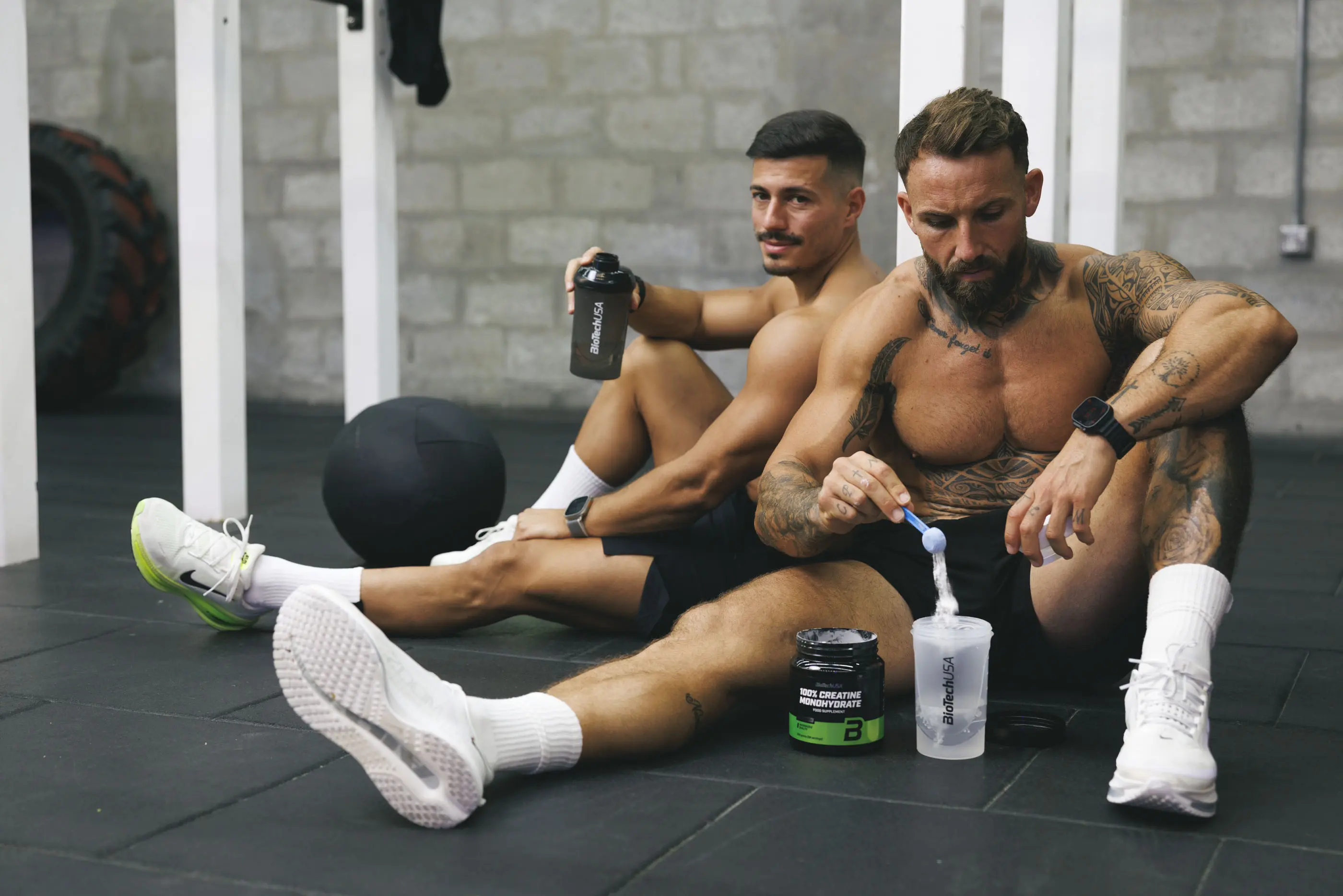 Dos atletas mezclan proteínas y aminoácidos en un mezclador después de entrenar