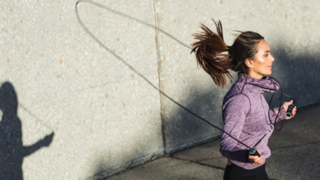 Persona saltando la cuerda al aire libre, destacando beneficios como mejora cardiovascular, quema de calorías y fortalecimiento muscular.