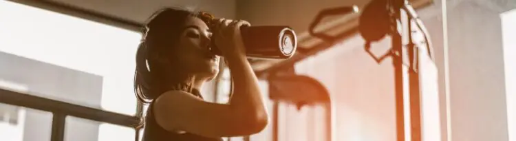 Mujer deportista sujetando batido con creatina antes de entrenar