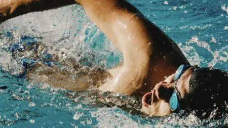 Deportista entrenando natación en piscina para mejorar fuerza y resistencia.