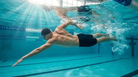 Nadador ejecutando crol con técnica perfecta, mostrando la activación muscular completa del cuerpo